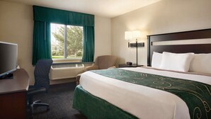 A hotel room with a bed, a desk, a chair, a TV, and a window with curtains.