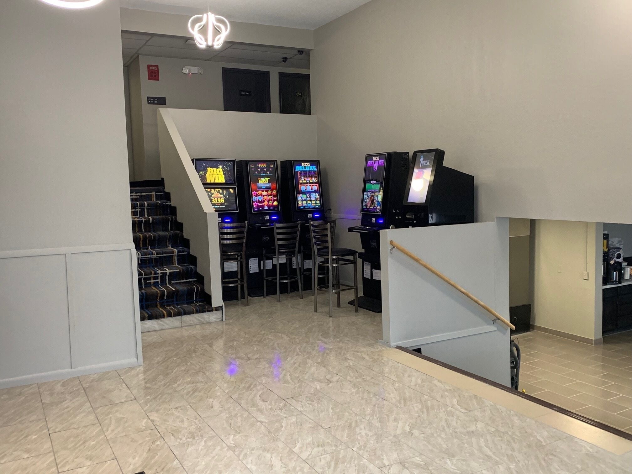 A gaming area with multiple slot machines and a staircase leading to an upper level.