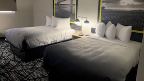 A hotel room with two beds, a nightstand with a lamp, and a window with blinds. - Super 8 by Wyndham Kirksville-University Area (Kirksville)