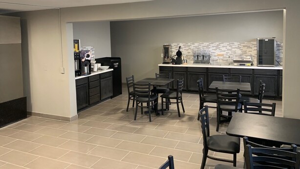 A modern kitchen with a dining area, featuring a kitchen island with appliances and a coffee station. - Super 8 by Wyndham Kirksville-University Area (Kirksville)