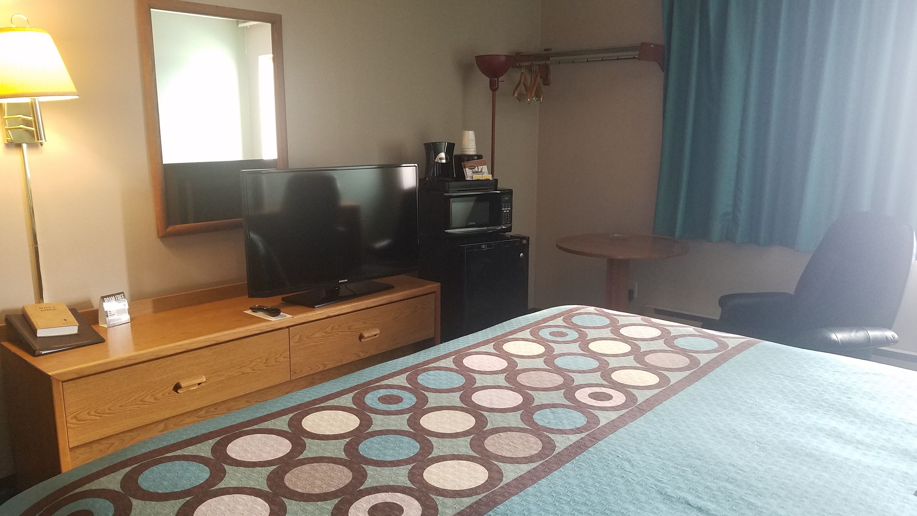 Une chambre d’hôtel équipée d’un lit, d’un bureau, d’une télévision, d’un four à micro-ondes et d’une machine à café.