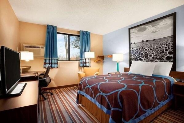 A hotel room with a bed, a desk with a computer, a chair, a TV, and a window with curtains. - Americas Best Value Inn Pittsburg (Pittsburg)