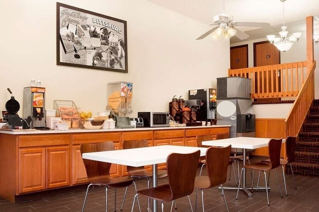 A modern kitchen with a central island, wooden cabinets, and a dining area with chairs.