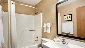 A bathroom with a shower, toilet, sink, and a large mirror. - Americas Best Value Inn Pittsburg (Pittsburg)