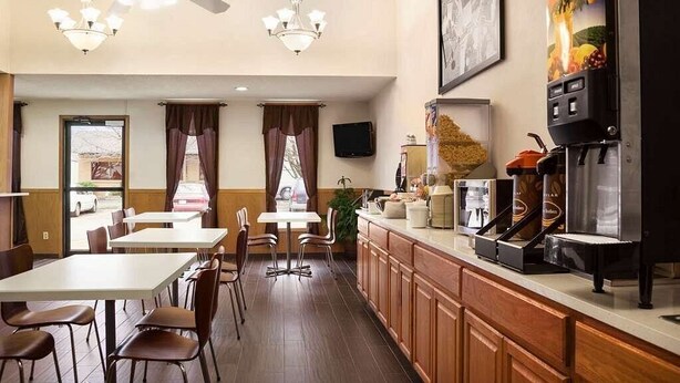 A hotel dining area with tables, chairs, a bar, and a coffee machine. - Americas Best Value Inn Pittsburg (Pittsburg)