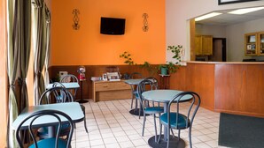 Ein Restaurant mit Theke, Tischen, Stühlen und einem an der Wand befestigten Fernseher.