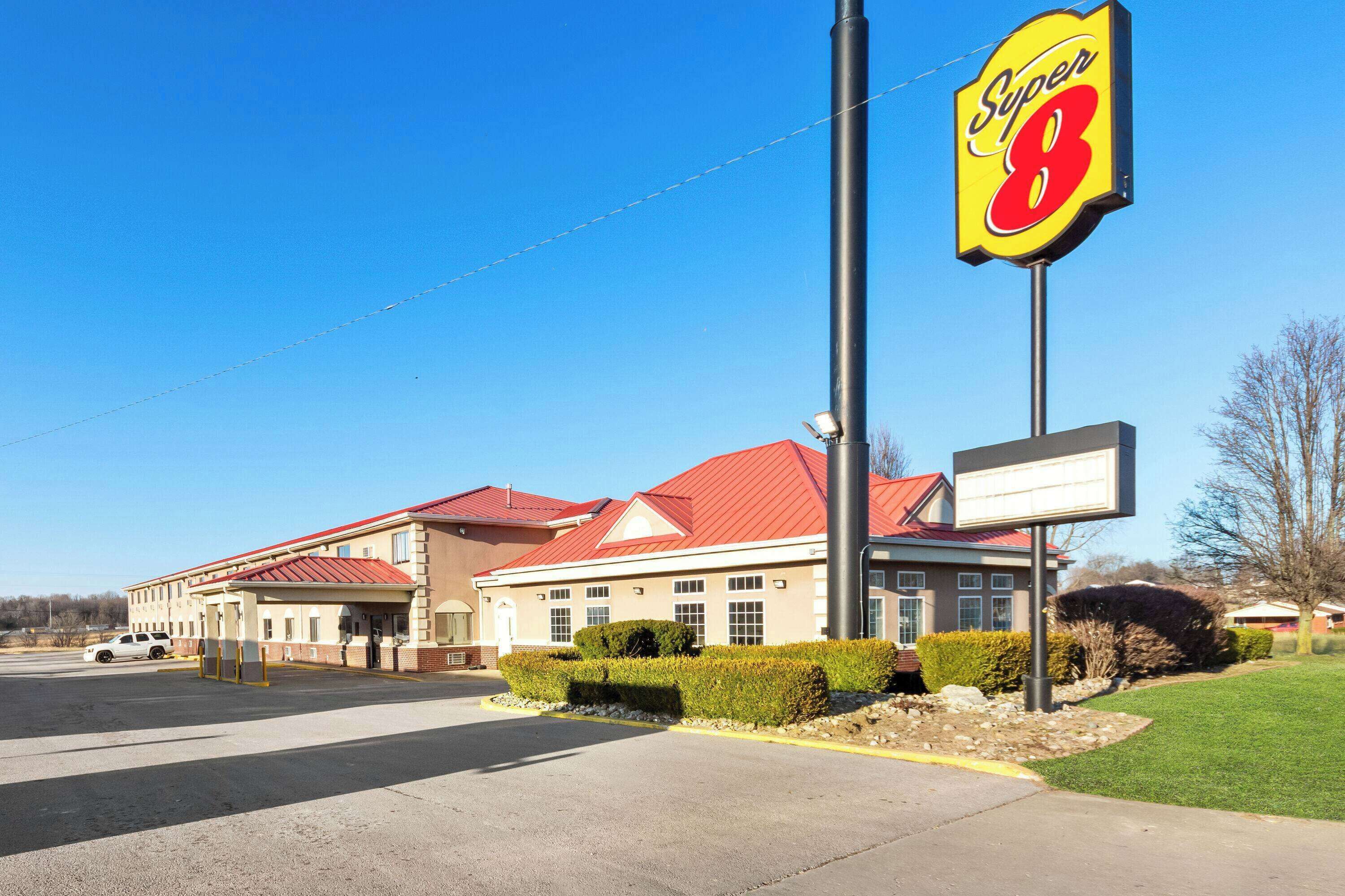 A Super 8 hotel with a red roof, a large sign, and a parking lot.
