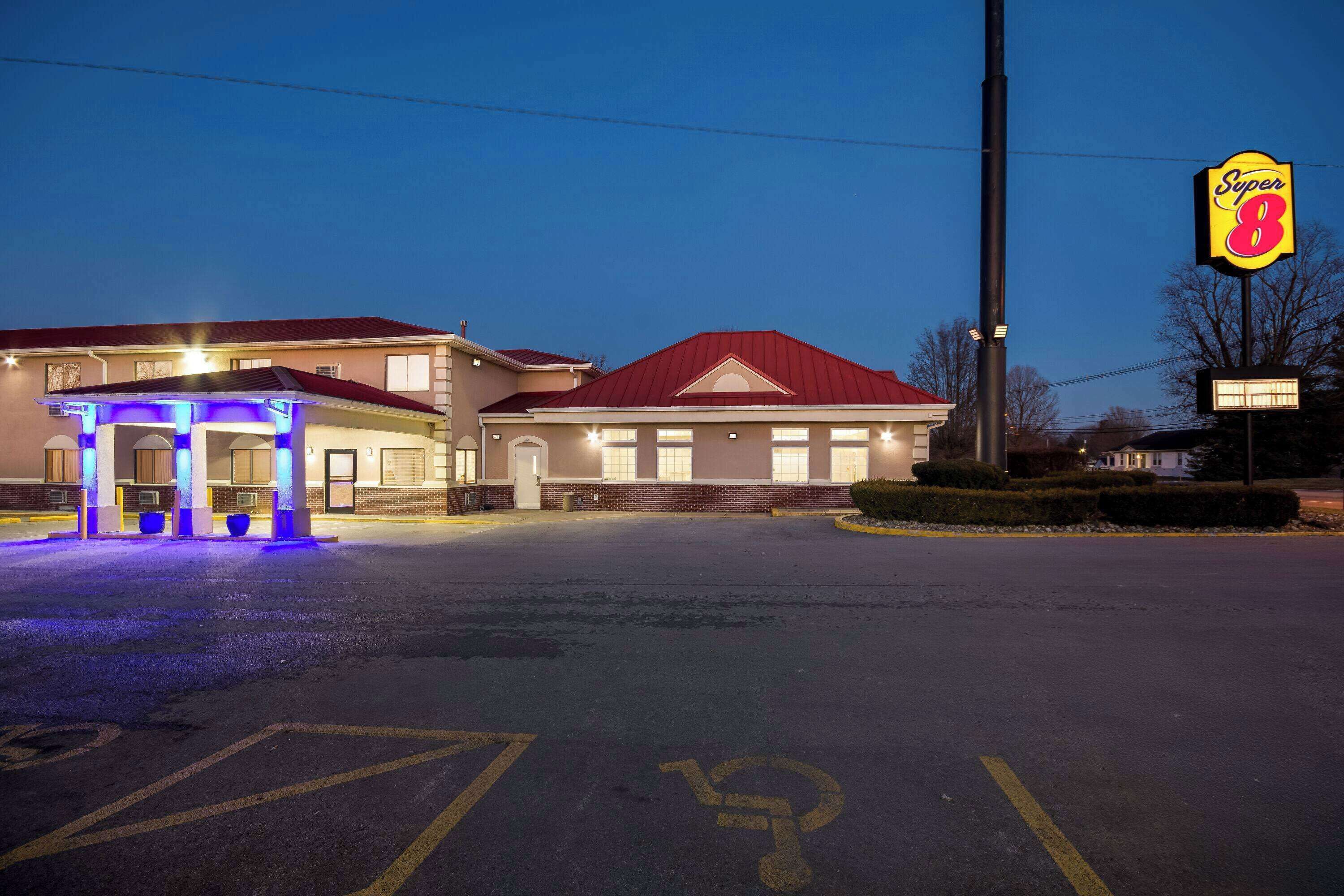 A hotel with a red roof, a Super 8 sign, and a parking lot with handicapped parking.