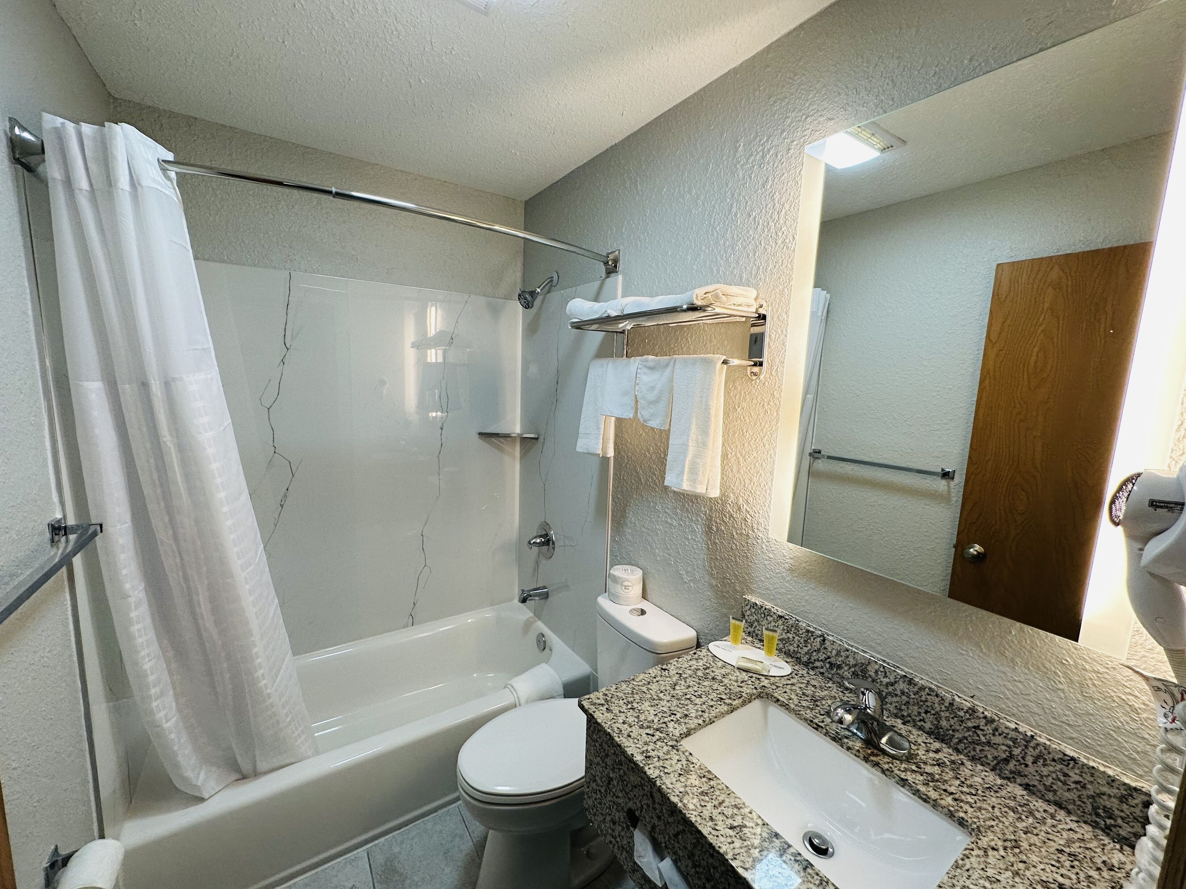 A bathroom with a bathtub, toilet, sink, and a towel rack.