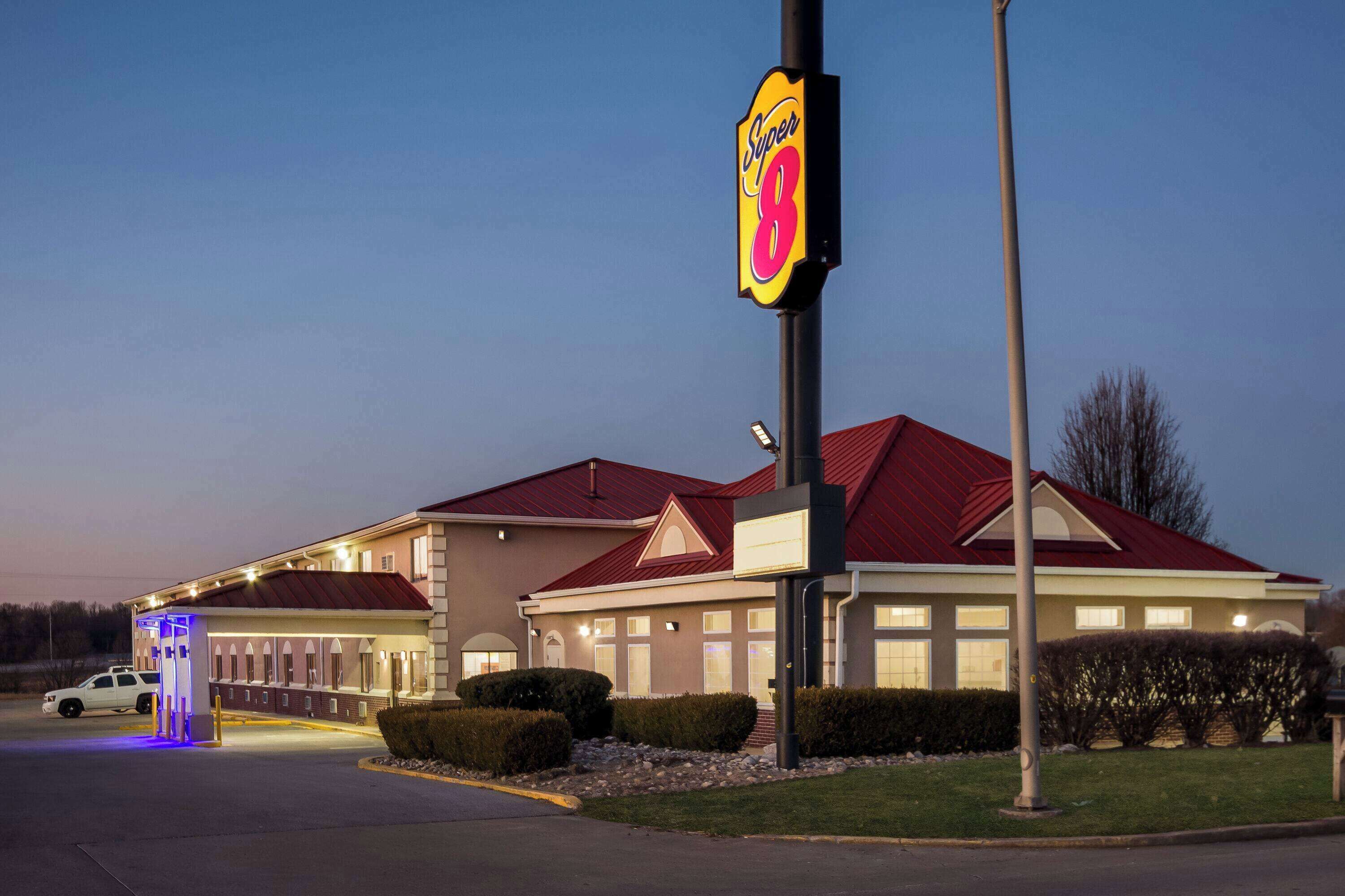 A Super 8 hotel with a red roof, a covered parking area, and a well-lit entrance.