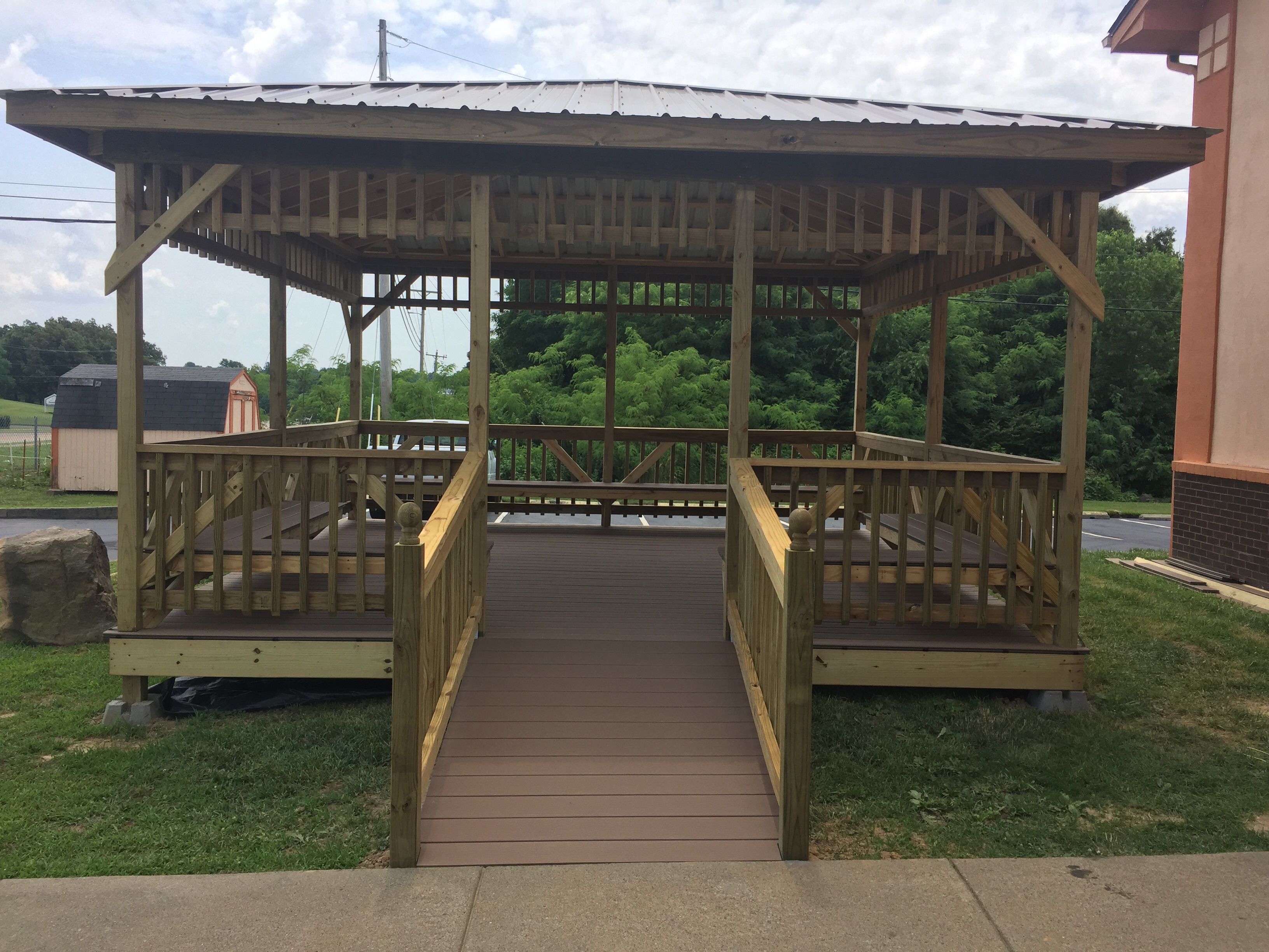 A wooden gazebo with a roof and a wooden deck.