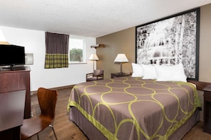 A hotel room with a large bed, a desk with a television, two lamps, a chair, and a large framed picture on the wall. - Super 8 by Wyndham Missoula/Brooks Street (Missoula)