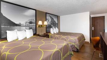 Ein Hotelzimmer mit zwei Betten, einem Schreibtisch und einem Sessel. Zwei Wandlampen und ein großes Bild einer Berglandschaft sind vorhanden.