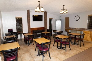A restaurant with wooden tables and chairs, a brick fireplace, and a clock on the wall.
