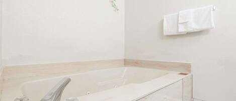 Une salle de bain moderne avec une grande baignoire, un seul robinet et un porte-serviettes.