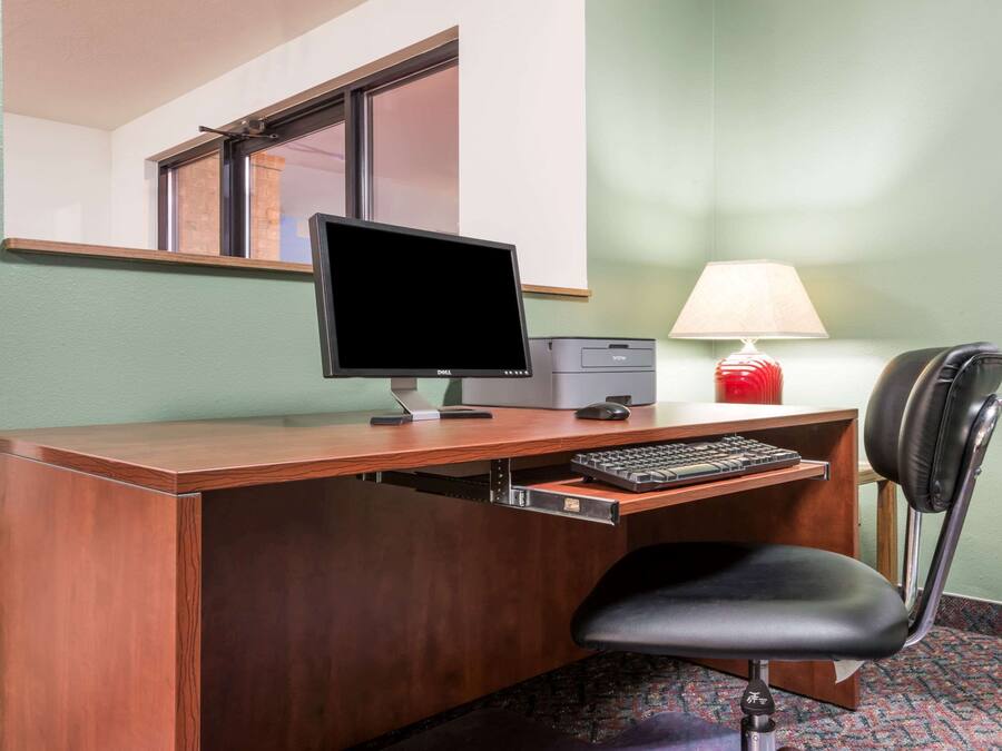 A wooden desk with a monitor, keyboard, and chair.