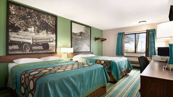 A hotel room with two beds, a desk, a chair, a lamp, and a window with curtains.