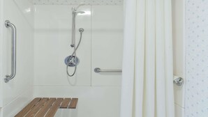Una dutxa amb una banca de fusta, barres de sujeció i un braç de pluja.