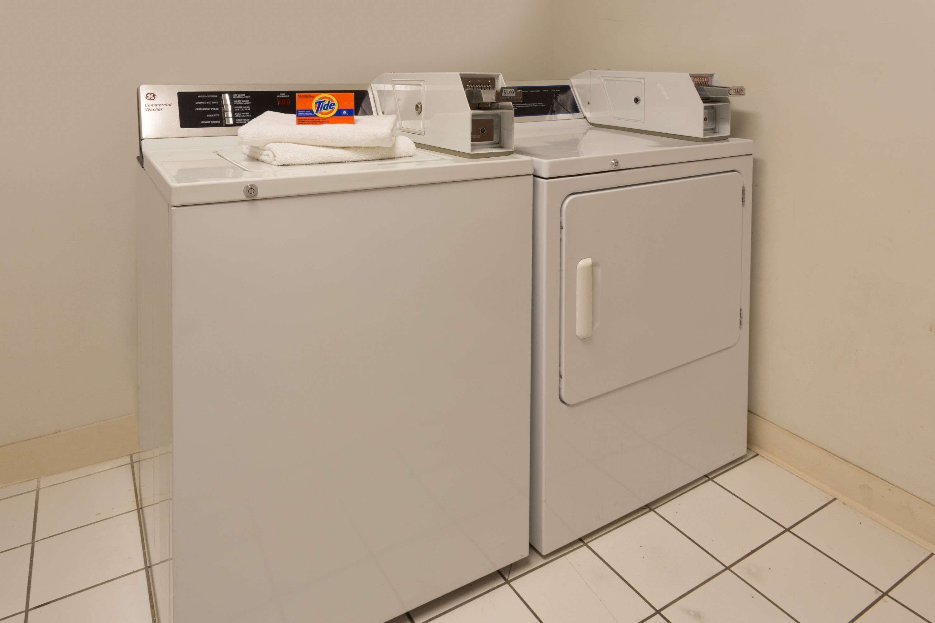 A front-loading washer and dryer unit with Tide detergent and a paper towel dispenser.