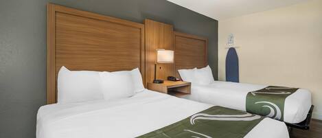 Una habitación de hotel con dos camas, una mesita de noche con lámpara y una decoración azul en la pared.