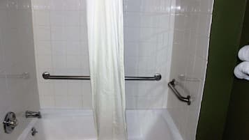 Un baño con paredes de azulejos blancos, una bañera y una cortina de ducha.