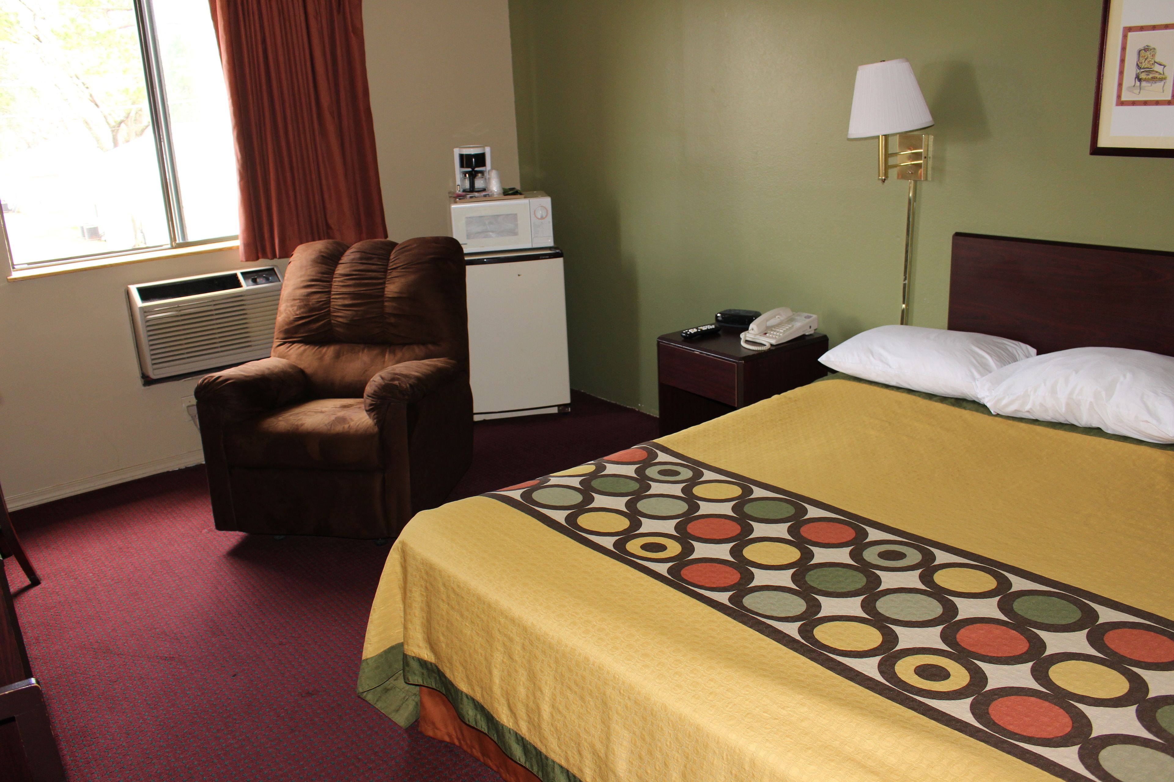 Une chambre d’hôtel équipée d’un lit, d’une chaise, d’un bureau, d’une lampe et d’un four à micro-ondes.