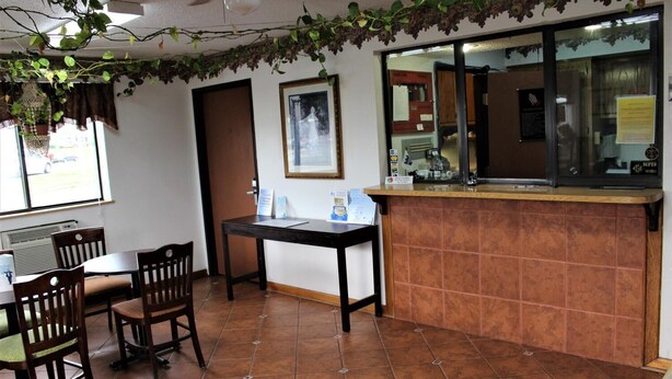 A restaurant with a wooden table and chairs, a tiled floor, and a counter with a menu. - Knights Inn Albany (Albany)