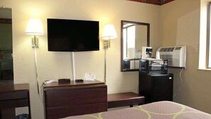 A hotel room with a bed, a dresser, a television, wall-mounted lamps, a coffee maker, and an air conditioner. - Knights Inn Albany (Albany)