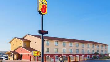 A Super 8 motel with a two-story building, a red roof, and a clear blue sky.