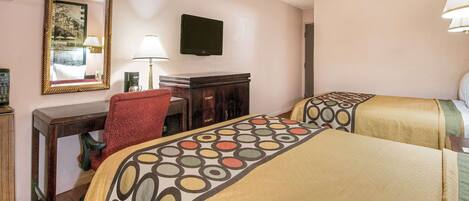 Habitación de hotel con dos camas, un escritorio con silla, televisor y espejo.