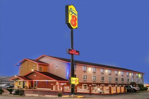 Un hotel Super 8 con un cartel que dice 'Desayuno Gratis', un estacionamiento y un edificio con múltiples ventanas y balcones.