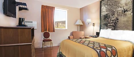Habitación de hotel con cama, escritorio, silla, televisor y ventana con cortinas.