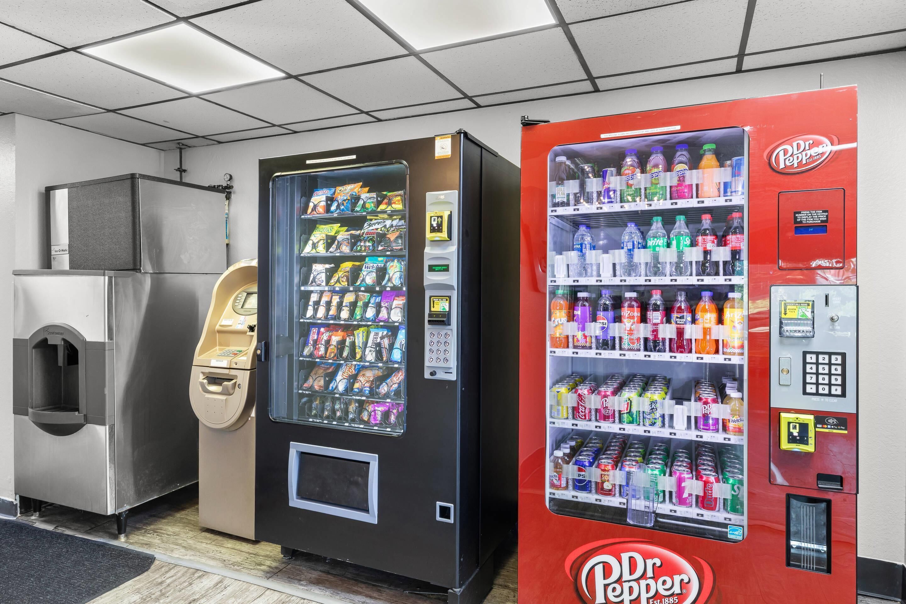 Three vending machines: a Dr. Pepper machine, a black machine with snacks, and a silver machine with a drink dispenser.