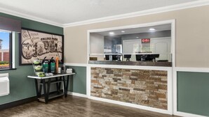 A reception area with a stone wall, a framed welcome sign, and a table with amenities. - Quality Inn Atlanta Airport - Central (College Park)