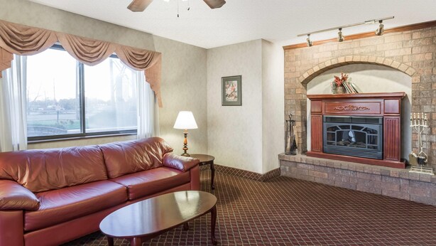 A living room with a leather sofa, a coffee table, a fireplace, and a window with curtains.