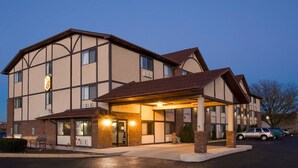 A hotel with a covered entrance, multiple windows, and a parking lot.