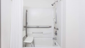 A modern bathroom with a walk-in shower, grab bars, and a white toilet.
