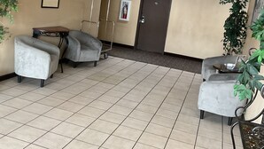 Un vestíbulo espacioso con techo alto, un balcón en el segundo piso y un extintor en la pared.