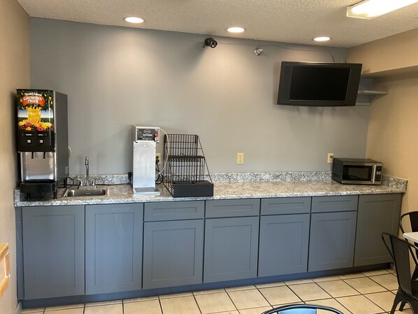 A kitchen with a coffee machine, microwave, and a TV mounted on the wall. - Super 8 by Wyndham Colorado Springs Airport (Colorado Springs)