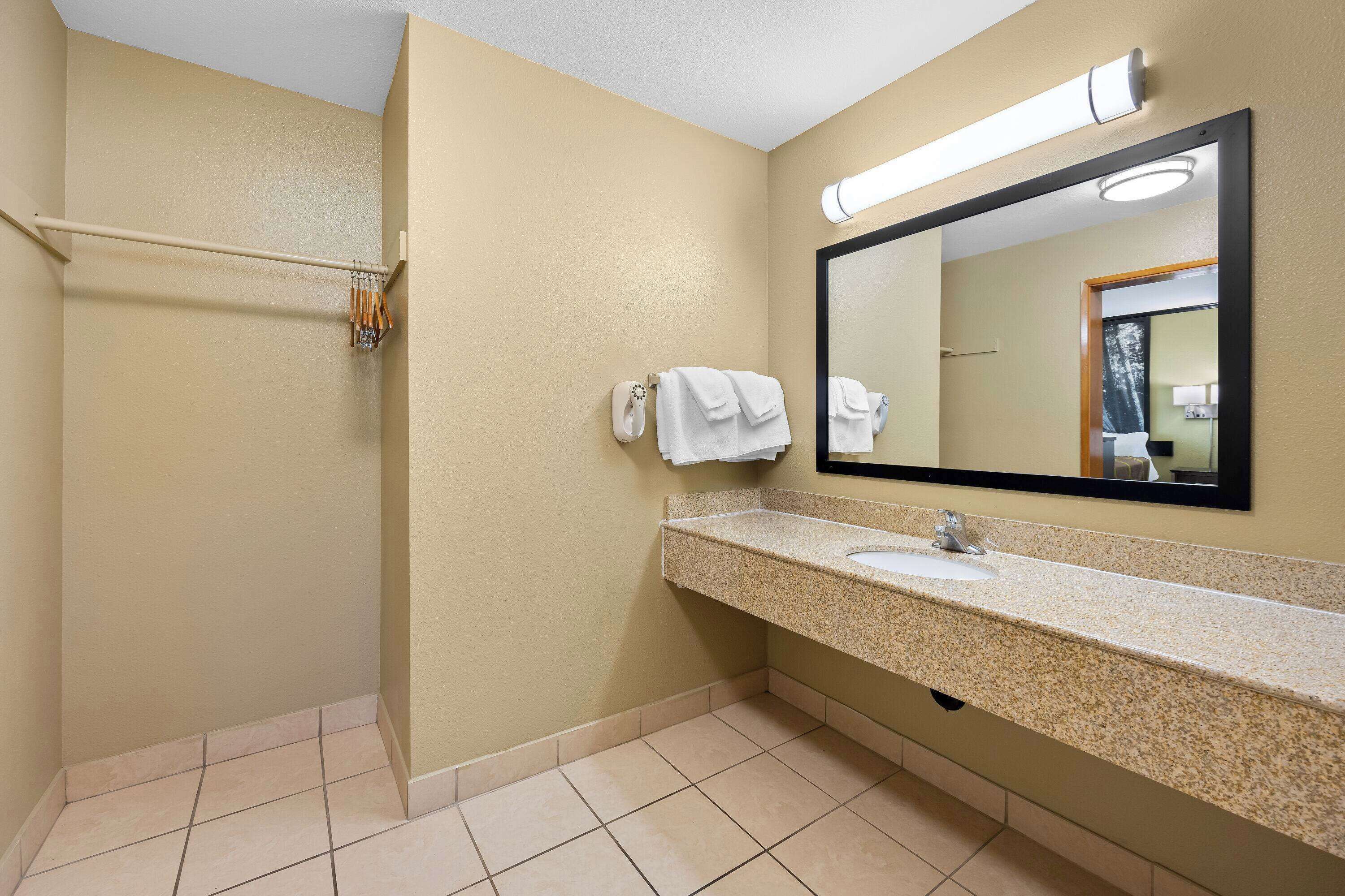 Une salle de bain équipée d’un lavabo, d’un miroir, d’un porte-serviettes et d’une zone douche.