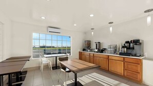 Eine moderne Küche mit einem großen Fenster, einem Essbereich mit Tisch und Stühlen sowie einer Kaffeestation.