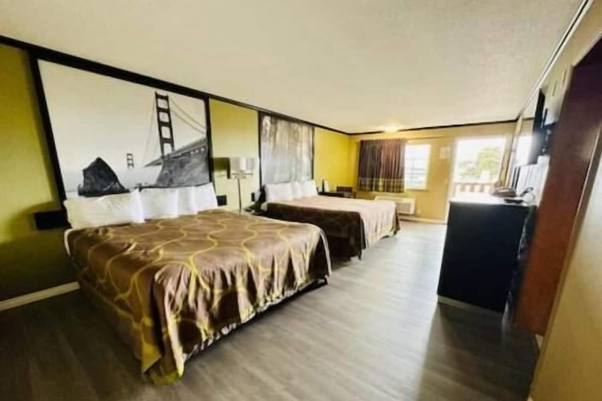 A hotel room with two beds, a desk, and a painting on the wall.