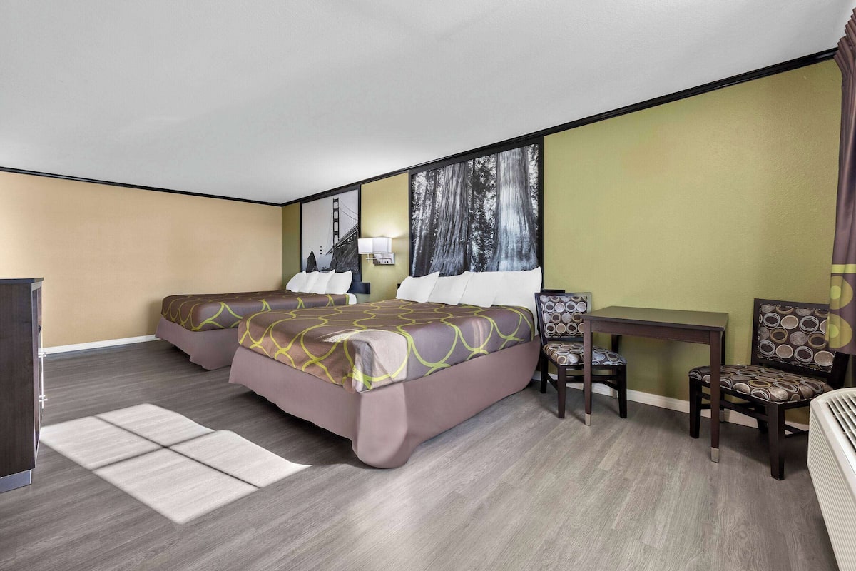 A hotel room with a large bed, two bedside tables, a desk, and a chair.