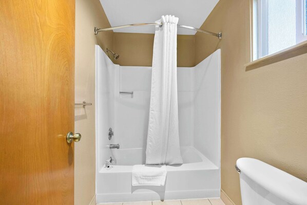A bathroom with a bathtub, toilet, and shower curtain.