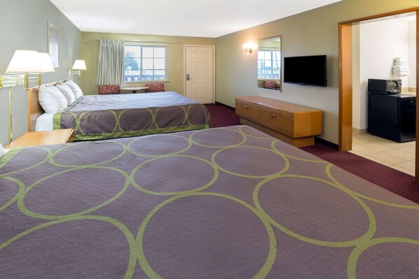 Ein Hotelzimmer mit zwei Betten, einem Fernseher, einem Schminktisch und einer Mikrowelle.