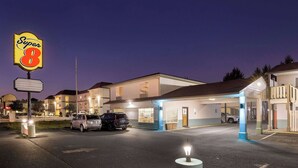 Ein Super 8 Hotel mit gut beleuchtetem Parkplatz und mehreren parkenden Fahrzeugen.