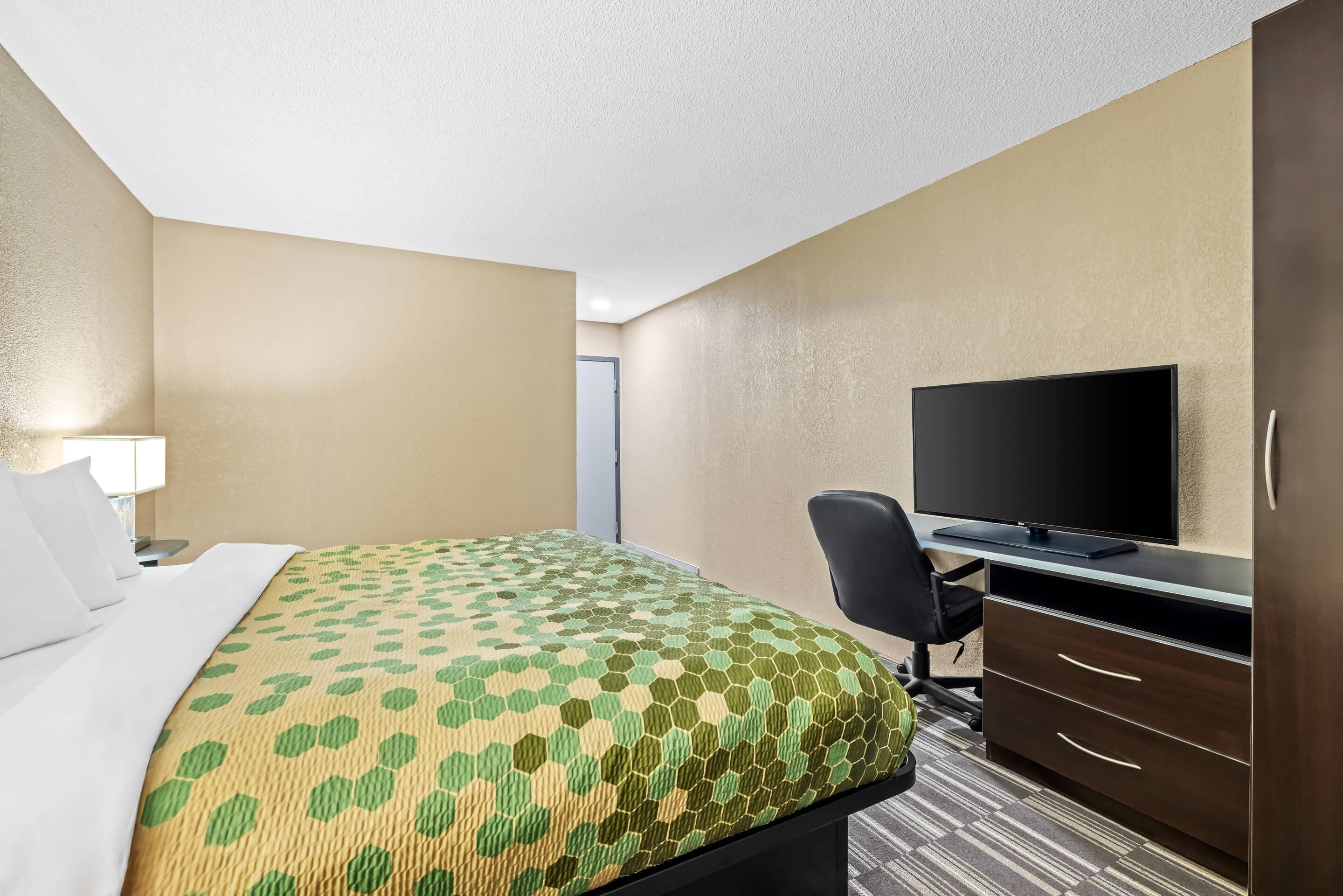 A hotel room with a bed, a desk, a television, and a wardrobe.