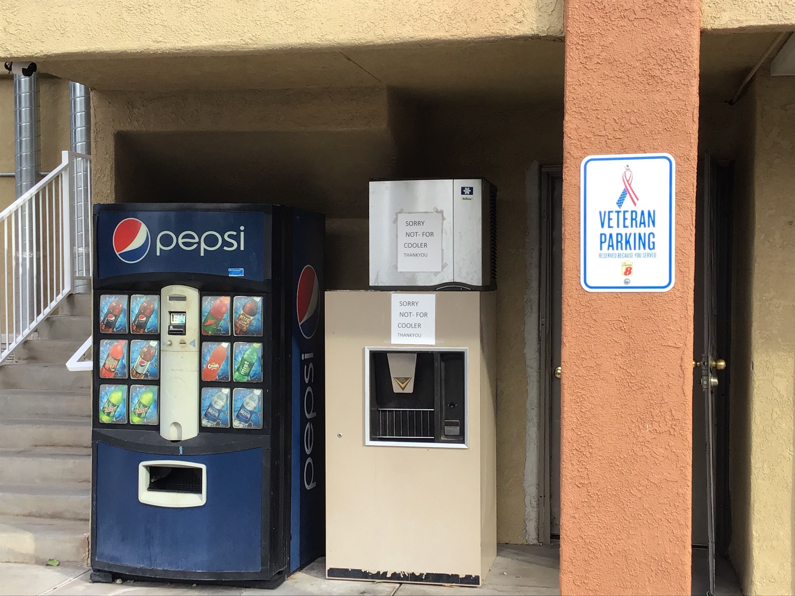 Een automaat met een Pepsi logo, een waterkraan en een bord met 'Veteran Parking'.