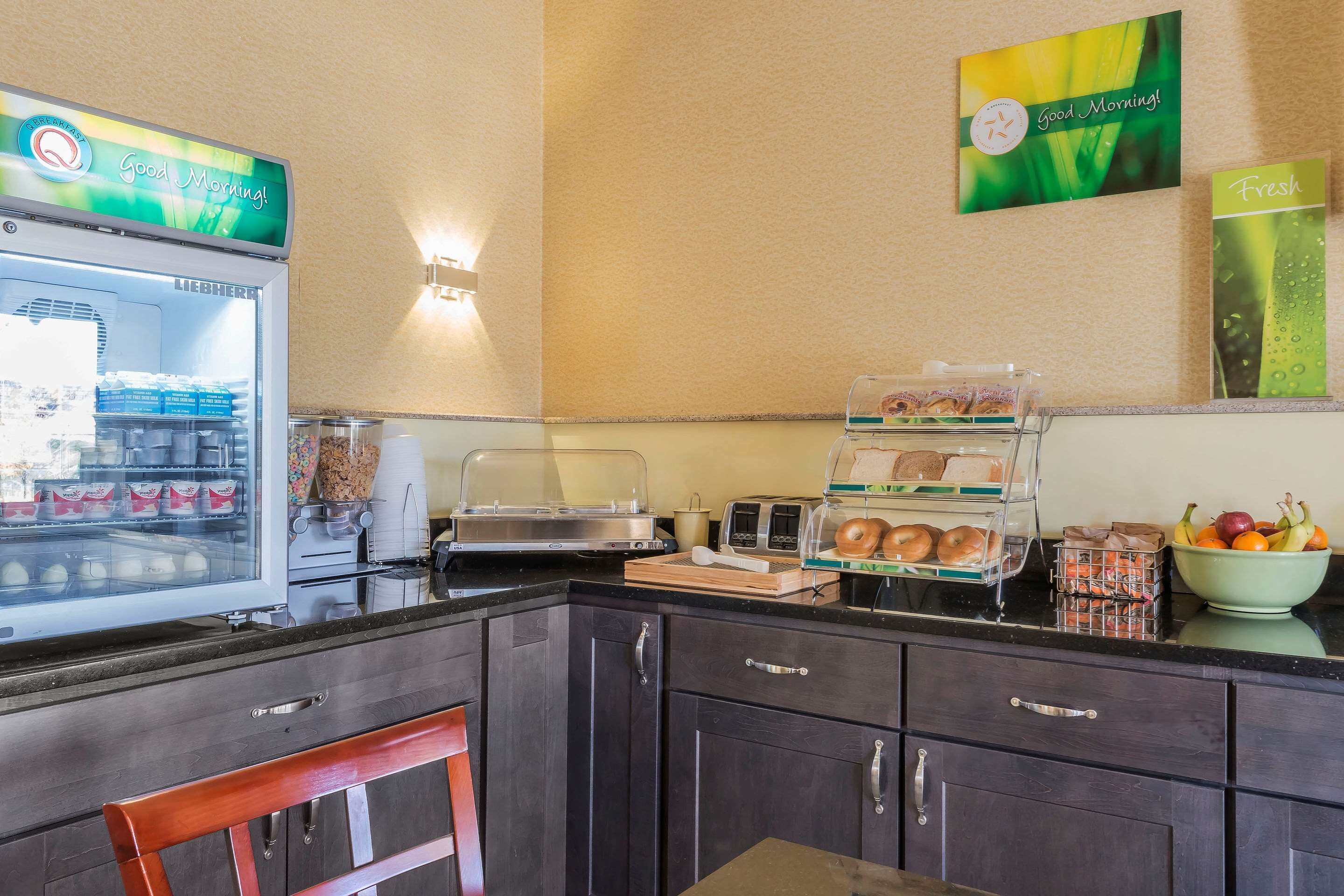 Una barra de desayuno equipada con un refrigerador lleno de bebidas, una cafetera y un frutero.