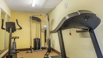 Un gimnasio con cinta de correr, elíptica y máquina de pesas.